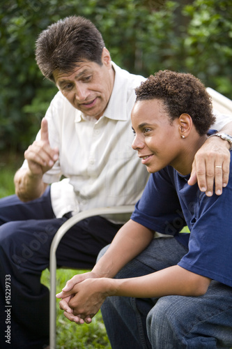 Photo: Interracial father and teenage son together in back yard Interracial father and teenage son together in back yard
