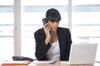 Jeune femme attentive au téléphone devant un ordinateur Jeune femme attentive au téléphone devant un ordinateur