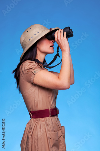 Photo: Woman in safari hat looking through binoculars side view Woman in safari hat looking through binoculars side view
