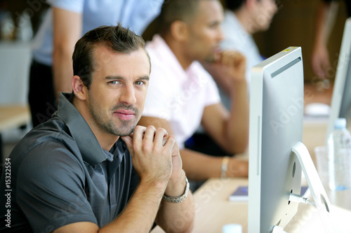 Portrait d'un homme souriant au bureau devant un ordinateur