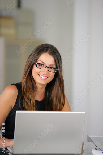 Femme d'affaires souriante assise devant un ordinateur portable