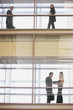 People in silhouette on multiple levels of corridor through glass