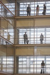 People in silhouette on multiple levels of corridor through glass