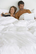 Woman in bed reading and man with laptop