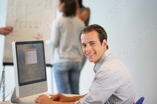 Portrait d'un homme souriant au bureau devant un ordinateur