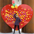A young woman with balloons in front of the big red heart