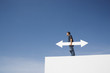 Man outdoors on wall with blank arrow