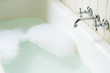 Old bath tube with bubbles, water and hot and cold tap