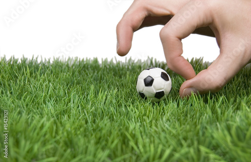 Foto: Hand mit Fußball auf grünem Rasen Hand mit Fußball auf grünem Rasen