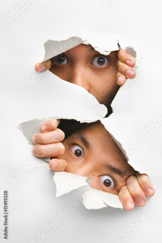 Foto: Two people peeking from hole in wall Two people peeking from hole in wall