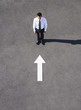 Arrow on pavement pointing toward businessman
