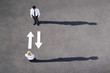 Arrows on pavement pointing to and away from businessman and woman