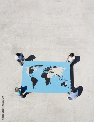 Photo: Four people holding world map outdoors Four people holding world map outdoors