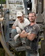 Two workers with water well drilling rig for geothermal energy