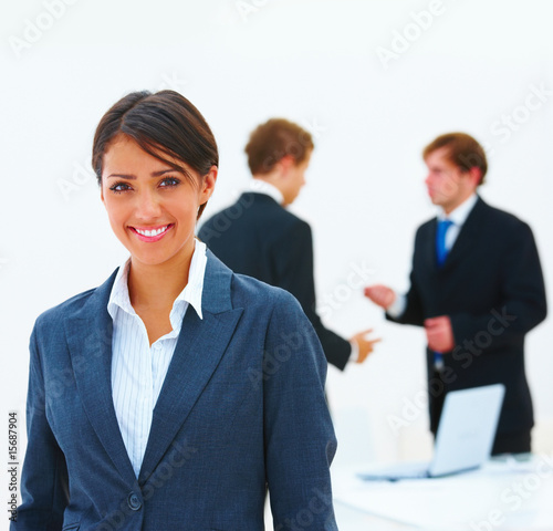 Photo: Happy young business woman with colleagues in the background Happy young business woman with colleagues in the background