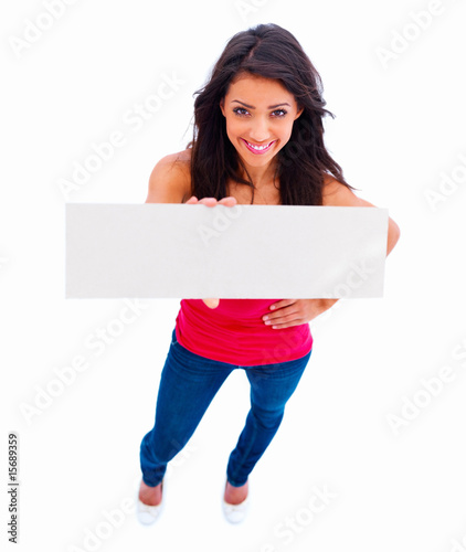 Photo: Happy beautiful woman holding a white board on white Happy beautiful woman holding a white board on white
