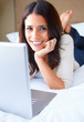 Closeup of a beautiful woman lying on bed and using laptop
