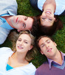 Top view of happy men and women lying on grass in a circle