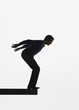 Man standing on a plank about to jump over ledge