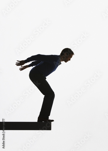 Photo: Man standing on a plank about to jump over ledge Man standing on a plank about to jump over ledge