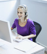 Businesswoman wearing a headset at her desk smiling