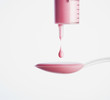 Medicine dropping out of a doser onto a spoon