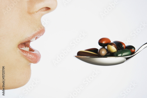 Photo: Woman taking a spoonful of pills Woman taking a spoonful of pills