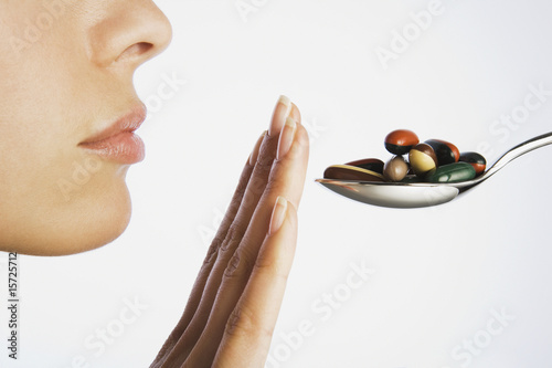 Photo: Woman with hand blocking spoonful of pills Woman with hand blocking spoonful of pills
