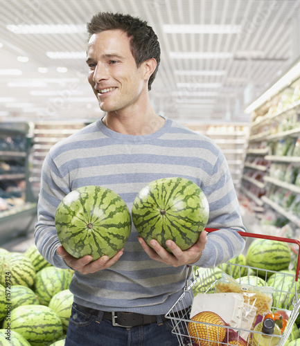 Photo: Man grocery shopping holding watermelons Man grocery shopping holding watermelons