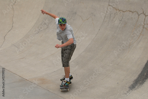 Photo: teenage skateboarder riding in cement half pipe teenage skateboarder riding in cement half pipe
