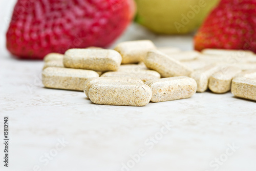 Photo: Prenatal vitamins with fresh fruit in the background. Prenatal vitamins with fresh fruit in the background.