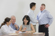 Meeting of five executives over paperwork.