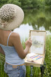 Young woman painting landscape in the open air