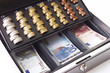 Cash box filled with coins and banknotes, elevated view, close-up