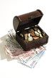 Open cash, full of coins, standing on bank notes, elevated view