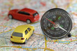 Toy cars and compass on city map, close up