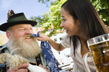 Photo: Germany, Bavaria, Upper Bavaria, Bavarian man and Asian woman in beergarden, Asian woman wiping man's beard Germany, Bavaria, Upper Bavaria, Bavarian man and Asian woman in beergarden, Asian woman wiping man's beard