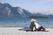Germany, Bavaria, Senior couple relaxing on lakeshore, sitting back to back