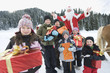 Photo: Italy, South Tyrol, Seiseralm, Children holding gift parcels, Santa Claus in background, portrait Italy, South Tyrol, Seiseralm, Children holding gift parcels, Santa Claus in background, portrait