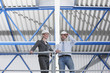 Photo: Germany, Neukirch, Man and woman architect standing in industrial hall, low angle view Germany, Neukirch, Man and woman architect standing in industrial hall, low angle view