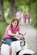 Germany, Bavaria, Young man on moped, persons in background