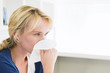 Close-up of a woman blowing her nose with a handkerchief