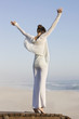 Woman standing on a boardwalk with her arms raised