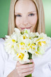 A portrait of a young blonde woman holding a bunch of daffodils