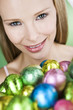 A young blonde woman holding a basket of Easter eggs, close-up