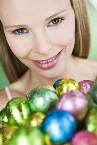 Photo: A young blonde woman holding a basket of Easter eggs, close-up A young blonde woman holding a basket of Easter eggs, close-up