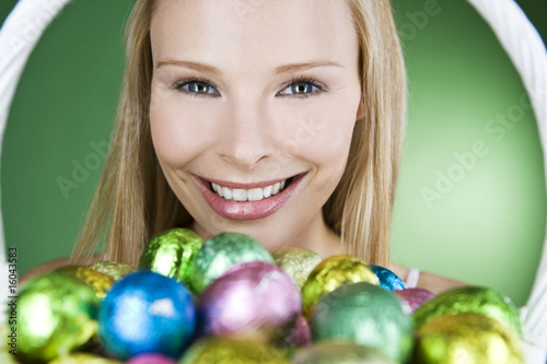 Photo: A young blonde woman holding a basket of Easter eggs, smiling A young blonde woman holding a basket of Easter eggs, smiling