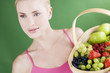A young woman holding a basket of fruit, looking to the side