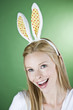 A young blonde woman wearing rabbit ears, smiling