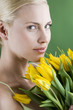 A young blonde woman holding a bunch of yellow tulips
